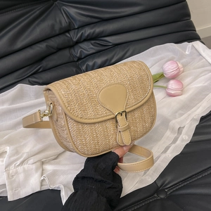 Close-up of khaki straw saddle bag with leather trim and gold adjustable buckle strap