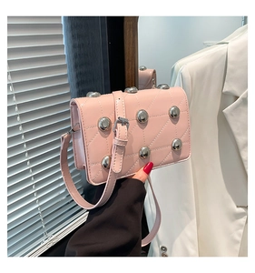 Detailed close-up of pink quilted crossbody bag with silver studs and adjustable strap