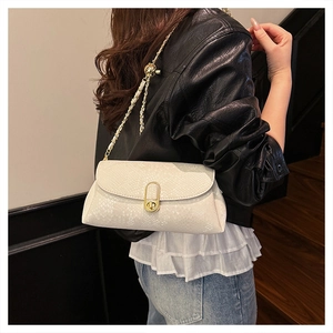 Detail of white snakeskin texture on a baguette bag with gold logo buckle and chain strap