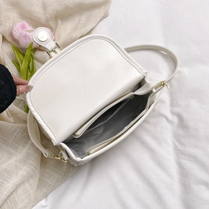 Interior view of the cream saddle bag showing the zipper pocket and magnetic closure