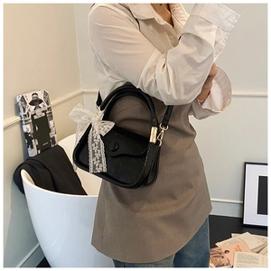 Close-up of black retro saddle bag with white lace bow and vintage button detail