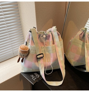Detail of multi-color striped drawstring bag with soft knit texture and plush charm