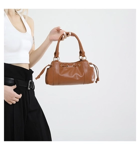 Detail of caramel brown faux leather tote bag with side drawstring knots and gold hardware