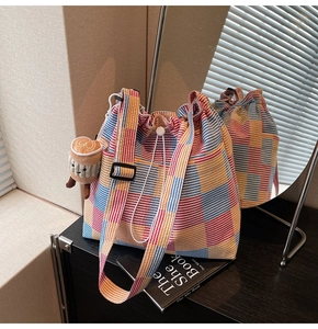 Detail of colorful striped canvas tote bag with drawstring closure and plush cup pendant