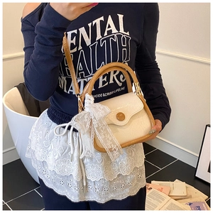 Detail of cream saddle bag with brown leather trim and elegant white lace bow decoration