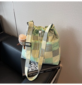 Detail of plaid canvas drawstring bucket bag with a cute coffee cup plush charm accessory