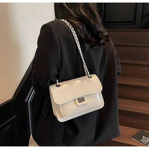 Close-up of a white quilted chain bag with silver turn-lock and V-shaped stitching