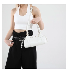 White faux leather bowling bag with gold hardware and drawstring detail on model