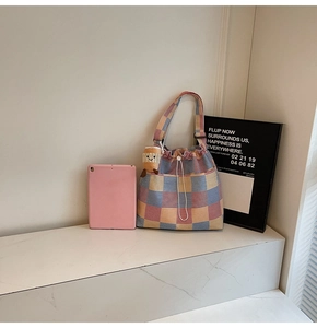 Detail of multi-color plaid canvas bucket bag with drawstring and plush charm