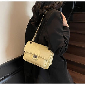 Detail of cream quilted crossbody bag with silver chain strap and metal turn-lock