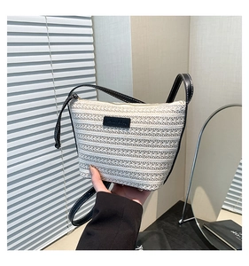 Detail of the woven bucket bag featuring black leather straps and white contrast stitching