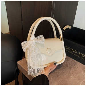 Detailed view of cream saddle bag with pleated leather and elegant lace bow detail