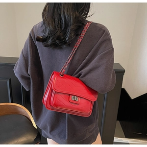 Detailed view of red quilted leather crossbody bag with silver chain and metal turn-lock