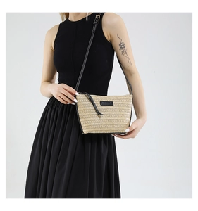 Close-up of woven straw bucket bag with black leather trim and metal zipper detail
