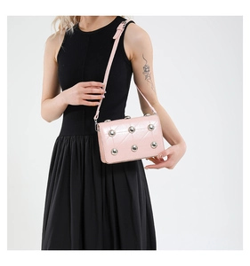 Detail of pink quilted shoulder bag with silver stud accents and adjustable strap