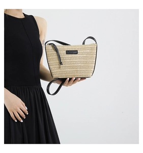 Detail of straw woven crossbody bag with black leather trim and white contrast stitching