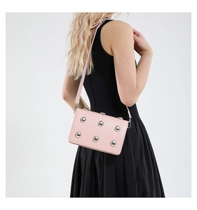 Pink crossbody bag with silver studs and quilted leather detail on black dress