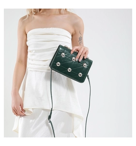 Detail of dark green vintage crossbody bag featuring silver studs and quilted leather