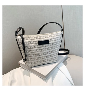 Detail of the woven straw texture and black leather strap on the off-white bucket bag