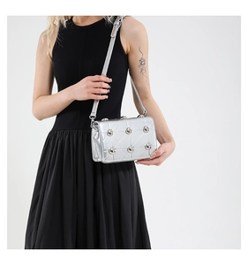 Detail of silver quilted crossbody bag featuring spherical metal studs and texture