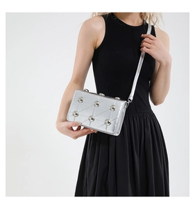 Detail of silver quilted crossbody bag featuring metal studs and slim shoulder strap