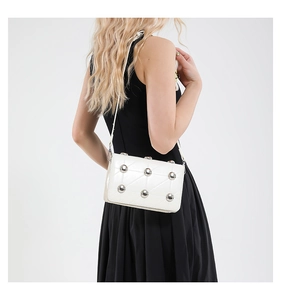 Detail of white leather crossbody bag with silver ball studs and quilted triangle stitching