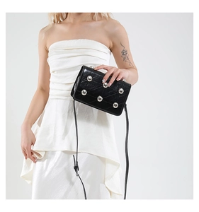 Close-up of black leather crossbody bag with silver studs and diagonal quilting detail