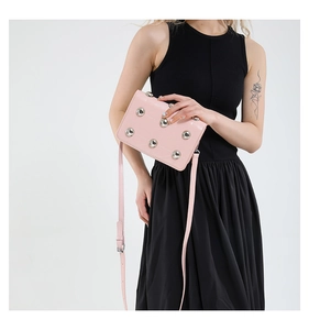 Pink rectangular crossbody bag with silver studs worn by model over black outfit