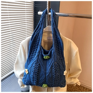 Détail du sac fourre-tout bleu en tricot avec décorations florales et motifs tissés