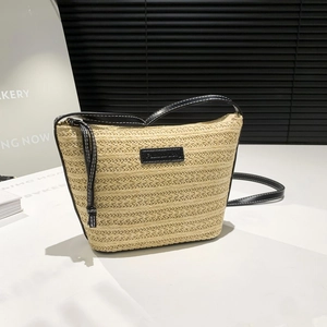 Beige woven bucket bag with black leather straps and fashion label in a modern setting