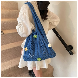 Detailed close-up of a blue hollow knit tote bag with handmade 3D crochet flower accents