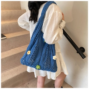 Gros plan du sac bandoulière en tricot bleu avec texture crochetée et fleurs