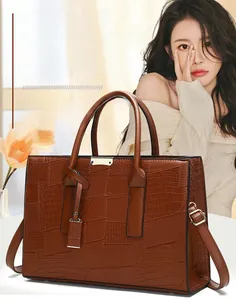 Macro detail of brown embossed crocodile texture and gold hardware on tote bag