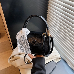 Chic black saddle bag with lace bow and gold hardware shown in a stylish lifestyle setting