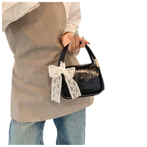 Elegant black saddle bag with lace bow handle and glossy wrinkled patent finish