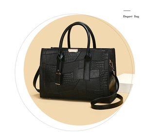 Detail of elegant black tote bag featuring embossed crocodile and litchi texture patchwork