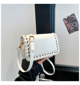 Close-up of white leather handbag with eyelets and woven side detailing for women
