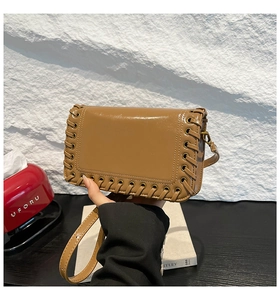 Detail view of caramel patent leather bag featuring woven edges and metallic eyelets