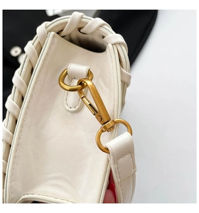 Macro detail of white leather shoulder bag with woven edge and vintage bronze lobster clasp