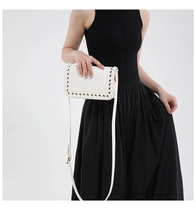 Detail of white leather shoulder bag featuring woven rope edge and golden metal hooks