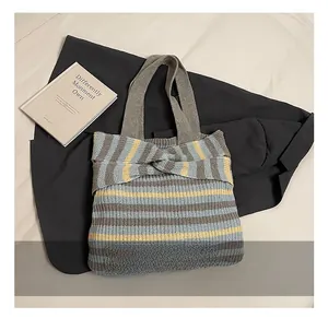 Detail of grey and yellow striped knit tote bag featuring a large decorative bow