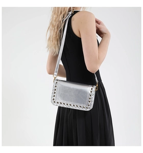 Close-up of silver crossbody bag featuring metal eyelets and woven leather strip detailing