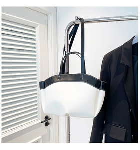 Detail of minimalist black and white tote bag with contrast stitching and soft leather texture