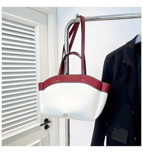 Detail of a half-moon leather handbag featuring red and white color-block design