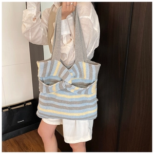 Close-up of knit tote bag featuring grey blue yellow stripes and 3D knot detail