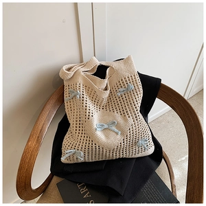 Détail d'un sac cabas en crochet beige avec des nœuds tricotés bleu clair sur maille