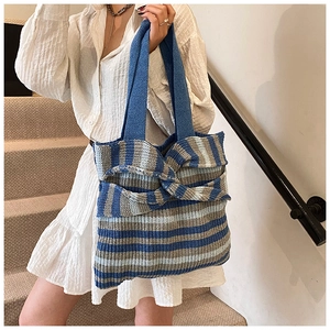 Detail of blue and grey striped knit tote bag with a large bow and soft blue handle