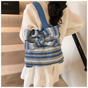 Macro view of blue and white striped knit tote bag featuring a large decorative bow
