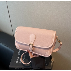 Close-up of pink pebbled leather shoulder bag with golden hardware and buckle detail