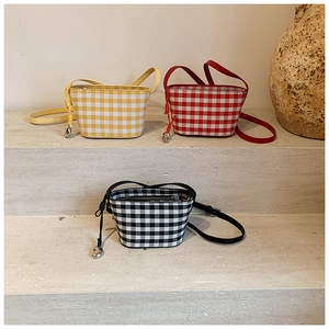 Three vibrant gingham canvas crossbody bags with heart charms on stone steps display